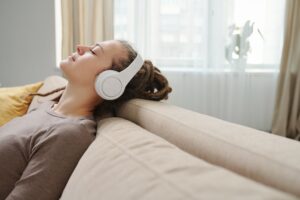 Young serene female with headphones enjoying music for relax on couch